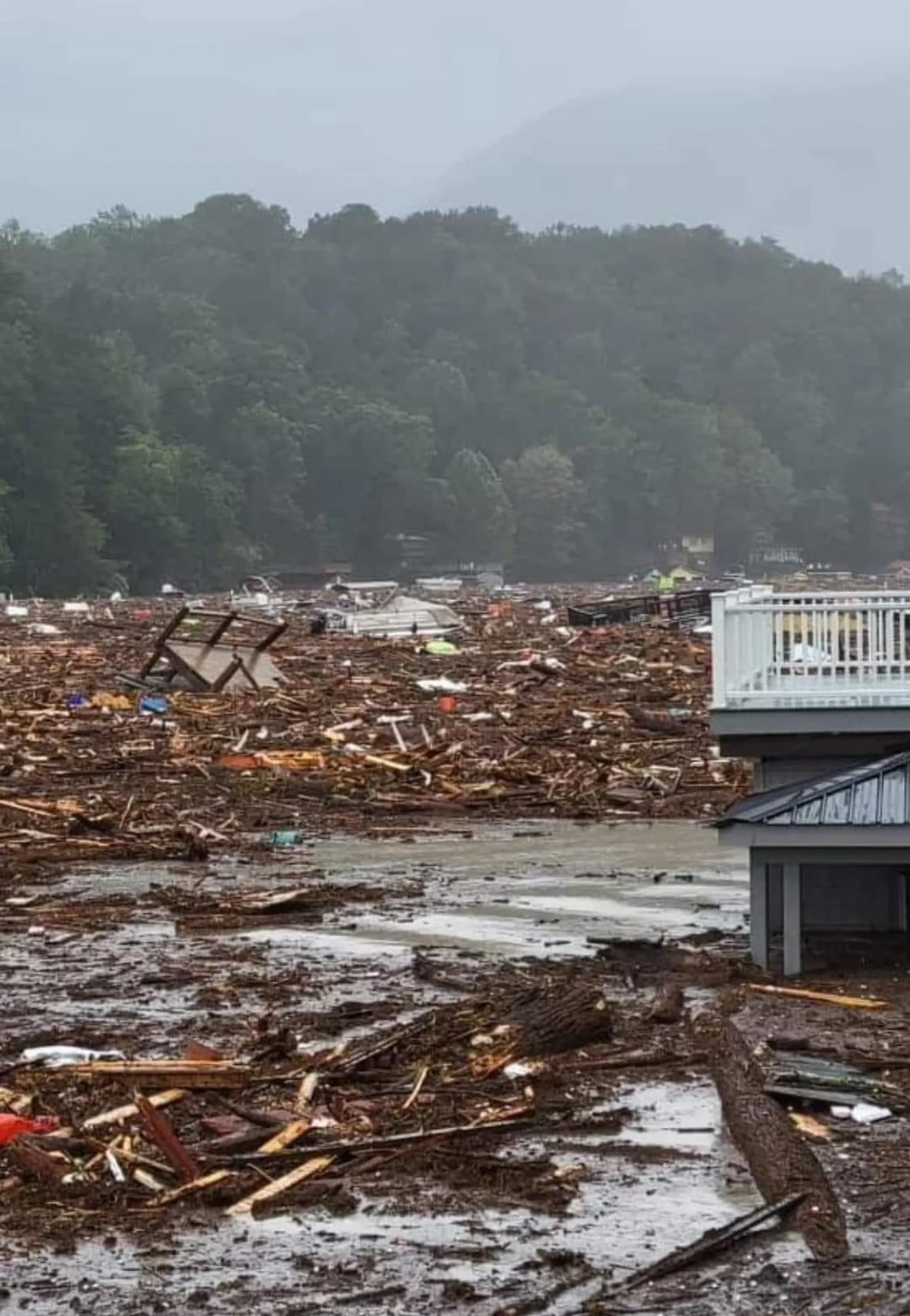 Widespread destruction with scattered debris, wooden wreckage, and damaged structures covering muddy ground after natural disaster